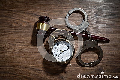 Handcuffs, judge gavel and alarm clock on the wooden background Stock Photo