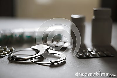 Handcuffs and pills and drugs on white table Stock Photo