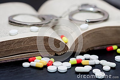 Handcuffs and pills and drugs on wooden table Stock Photo