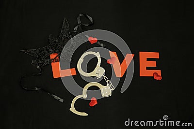 Handcuffs for sex games and hearts on black background. Sexual bdsm toy Stock Photo