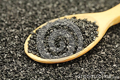 A handful of crushed coal in a wooden spoon Stock Photo