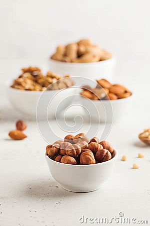 A handful of hazelnuts in a white bowl, assorted nuts on a light background. Healthy snacks, healthy fats. Copy space Stock Photo
