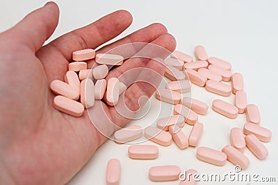A handful of pink pills. Man holds vitamins in the palm of his hand Stock Photo
