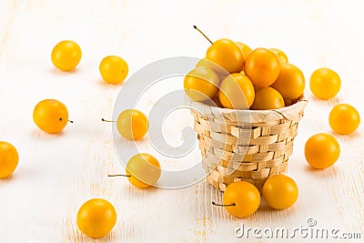 Handful of yellow cherry plums in basket Stock Photo