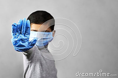 Handgesturing stop - 7 years old boy in medical face mask and gloves Stock Photo