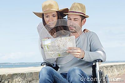 Handicapped man in wheelchair and girlfriend looking at map Stock Photo