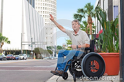 Handicapped man in a wheelchair hailing a taxi in the city Stock Photo