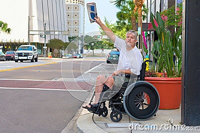 Handicapped man in a wheelchair hailing a taxi waving newspaper Stock Photo