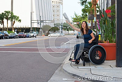 Handicapped woman in a wheelchair hailing a taxi waving newspaper Stock Photo