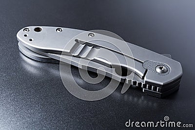Handle Of A Closed Faint Military Knife Lying On Dark Ground With Reflection Stock Photo