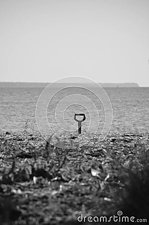 Forgotten shovel on the river bank. monochrome metaphor Stock Photo