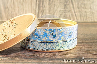 Handmade candle made in the golden rounded box decorated with textured fabric. Stock Photo