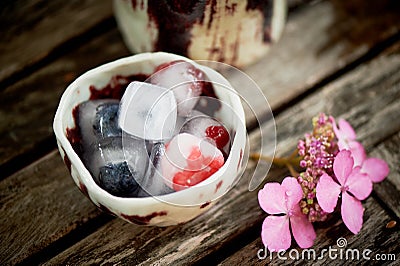 Handmade ceramics. Ice cubes, frozen berries, on wooden background.Freshness, rustic Stock Photo