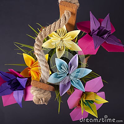 Handmade colored paper flowers origami bouquet paper craft art in a basket with grass in the studio on blackbackground Stock Photo