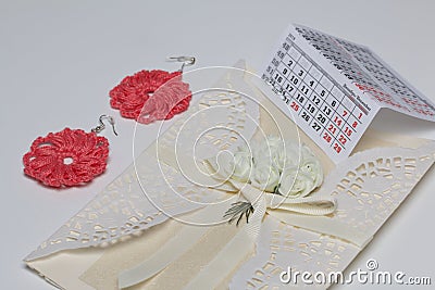 Handmade crocheted earrings. Greeting card. Nearby is a fragment of the calendar with the month of December. On white background Stock Photo