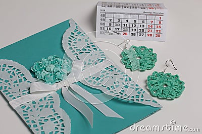 Handmade crocheted earrings. Greeting card. Nearby is a fragment of the calendar with the month of December. On white background Stock Photo