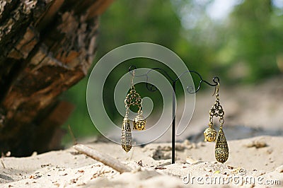 Handmade. Earrings on the stand with buddhas on sand Stock Photo