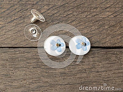 Handmade epoxy resin jewelry. forget-me-not flowers. earrings. on a wooden background Stock Photo