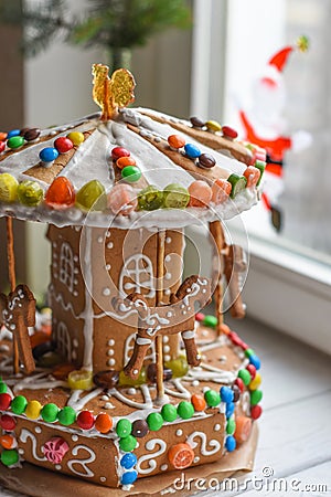 A gingerbread carousel and some Christmas decoration elements on a white wooden surface Stock Photo