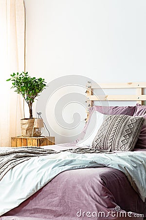 Handmade lamp and fresh plant standing on wooden bedside table n Stock Photo