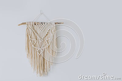 Handmade macrame decoration hanging on a white empty wall. Stock Photo