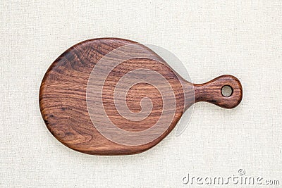 Handmade North American black walnut wooden chopping board on sackcloth. Walnut wood chopping board texture. Stock Photo