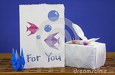 Handmade origami swans, card with origami fish together with Furoshiki fabric wrapped gift Stock Photo