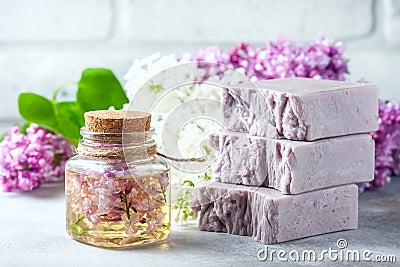 Handmade soap, Glass jar with fragrant oil and lilac flowers for spa and aromatherapy. Stock Photo