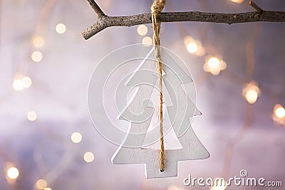 Handmade Wood White Christmas Tree Ornament Hanging on Branch. Glittering Garland Lights. Pastel Colors.New Year Greeting Card Stock Photo