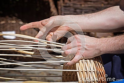 Hands of a basket maker are braiding a wicker basket Stock Photo