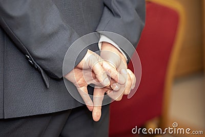 hands behind the back of an adult man in a gray suit with a jacket Stock Photo