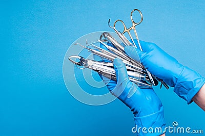 Hands in blue gloves holding dental equipment and metal instruments Stock Photo