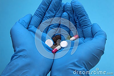 Hands in blue medical gloves hold pills in the palm of their hand Stock Photo