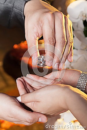 Hands of the bride and groom placing wedding rings Stock Photo