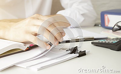 Hands of businessman hold pen for work in stacks of paper files, information search for business reports and heaps o Stock Photo