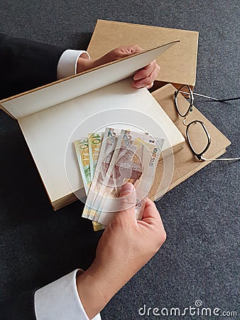 hands of a businessman with peruvian money and books on the table Stock Photo