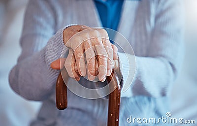 Hands, cane and disability with a senior woman closeup in her home alone with a walking stick for mobility. Health Stock Photo