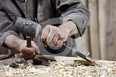 Hands of carpenter with a hammer and chisel on workbench in carpentry Stock Photo