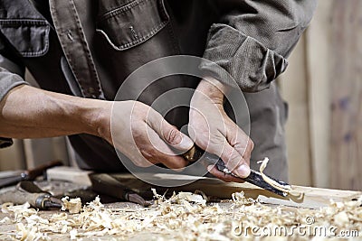 Hands of carpenter with a hammer and chisel on workbench in carpentry Stock Photo