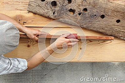 Hands carpenter working a wooden rustic old board with a sand pa Stock Photo