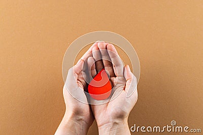 Hands of caucasian woman cupping blood drop on brown background Stock Photo