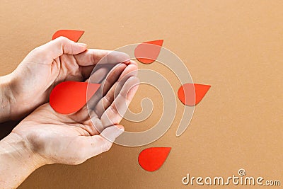 Hands of caucasian woman cupping blood drop, with blood drops on brown background, copy space Stock Photo