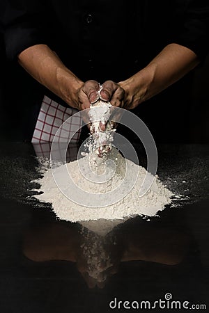 Hands chef black cloth knead white flour dough on a table Stock Photo