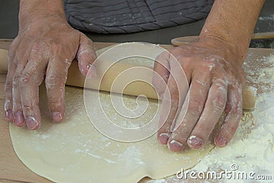 The hands of the chef knead the dough on a wooden table Stock Photo