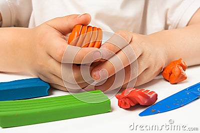 Hands of child molding from orange plasticine Stock Photo