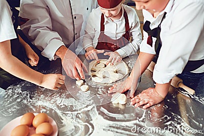 Hands of children close-up cook a cookie on the table. Stock Photo