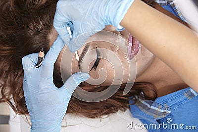 Hands close-up, microblading, wiping, cleaning eyebrow with swab, from pencil line Stock Photo