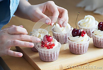 hands close-up of young woman pastry chef decorates cupcakes with berries Stock Photo