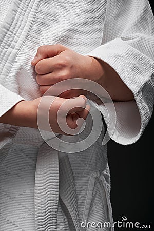 Hands closeup - teenager dressed in martial arts clothing posing on a dark gray background, a sports concept Stock Photo