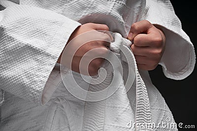 Hands closeup - teenager dressed in martial arts clothing posing on a dark gray background, a sports concept Stock Photo